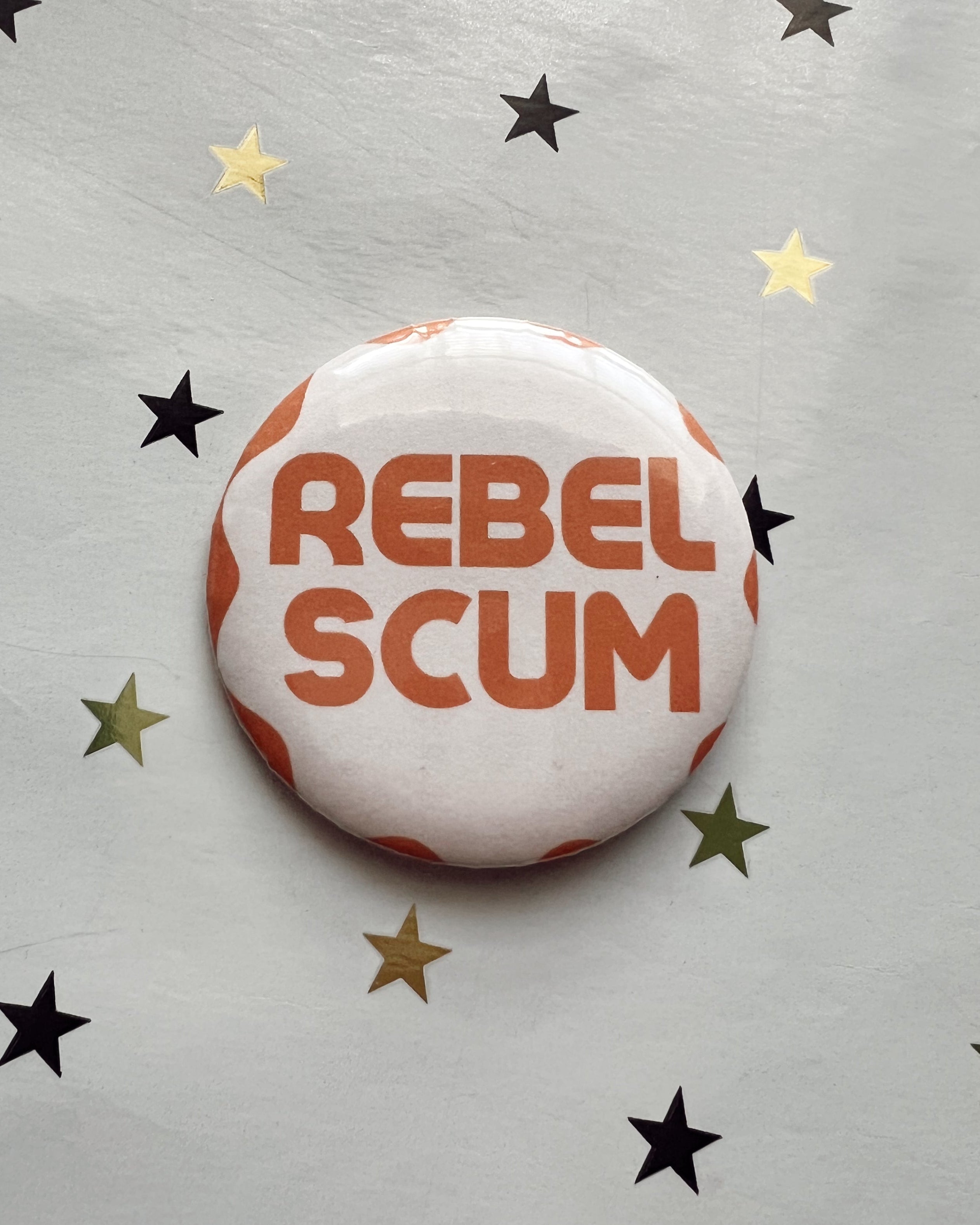 Button badge with 'REBEL SCUM' text on a star-patterned background