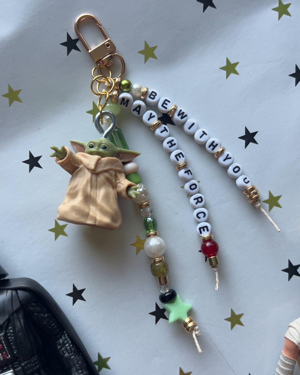 Keychain with Baby Yoda figure and 'BewiththeForce' beads on a star-patterned background