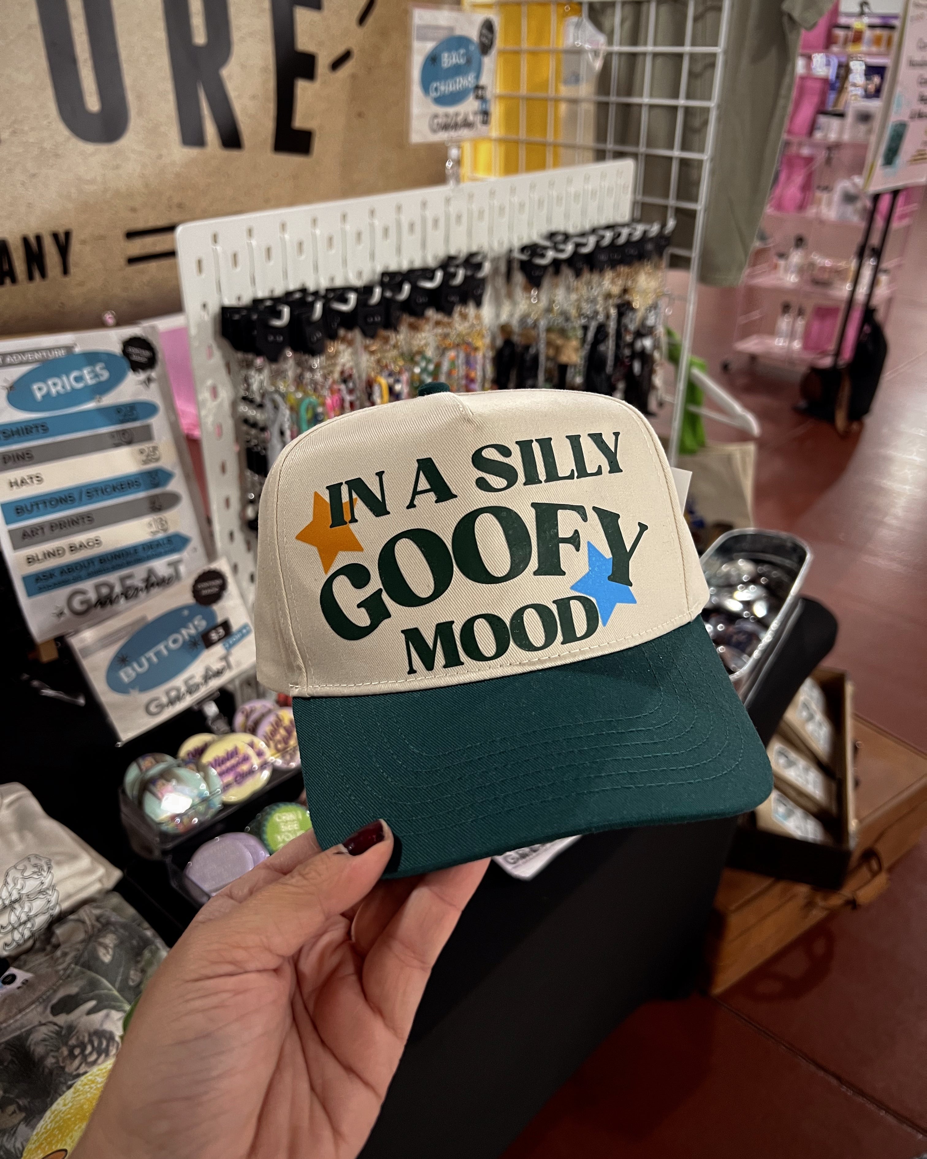 Cap with 'In a Silly Goofy Mood' text held in a store setting